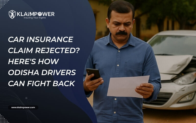An Indian man stands in front of a damaged car, holding a phone and a rejection letter, appearing concerned after his car insurance claim was denied.